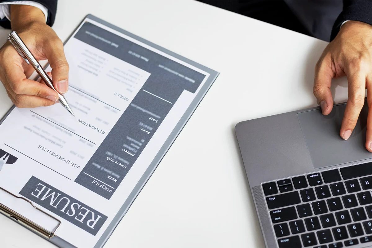 Image of a person marking a resume and entering information into a computer