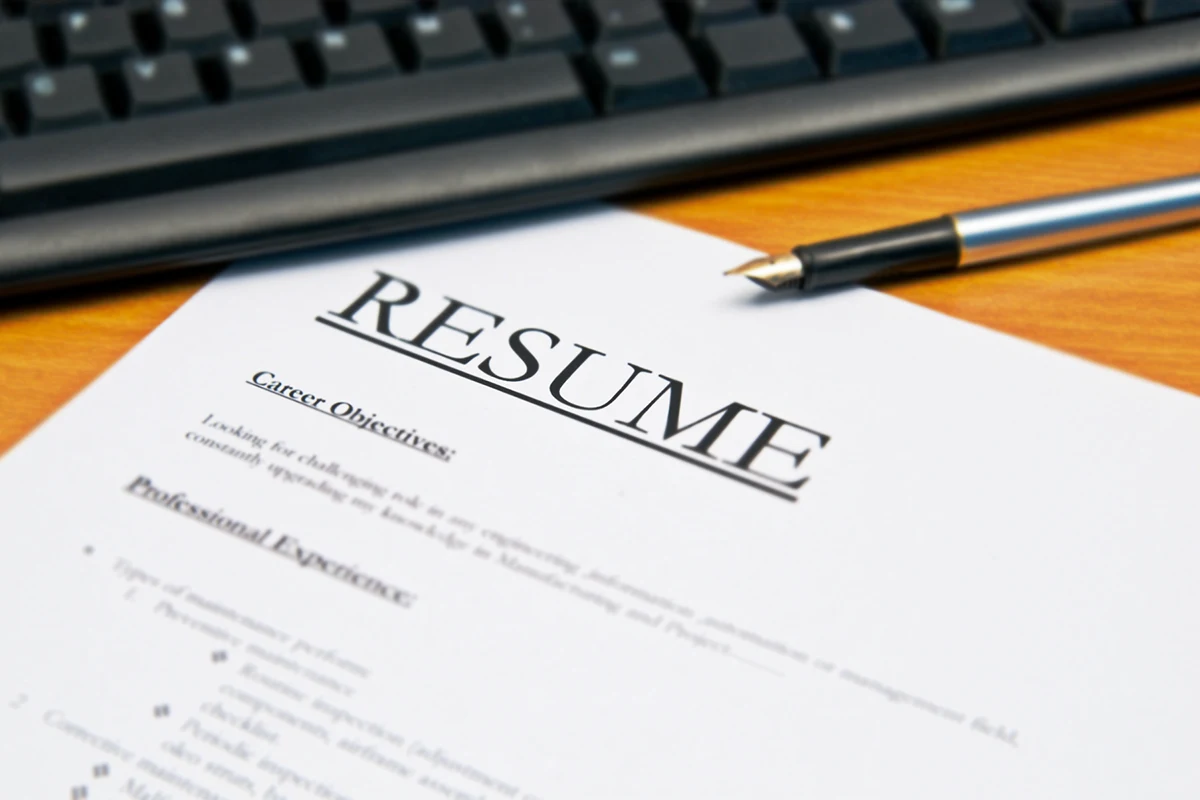 Image of a resume on a table with a keyboard and a pen